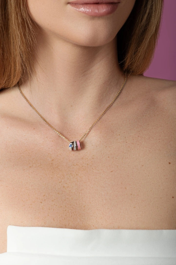 Necklace with a colorful pendant worn by a person against a pink background